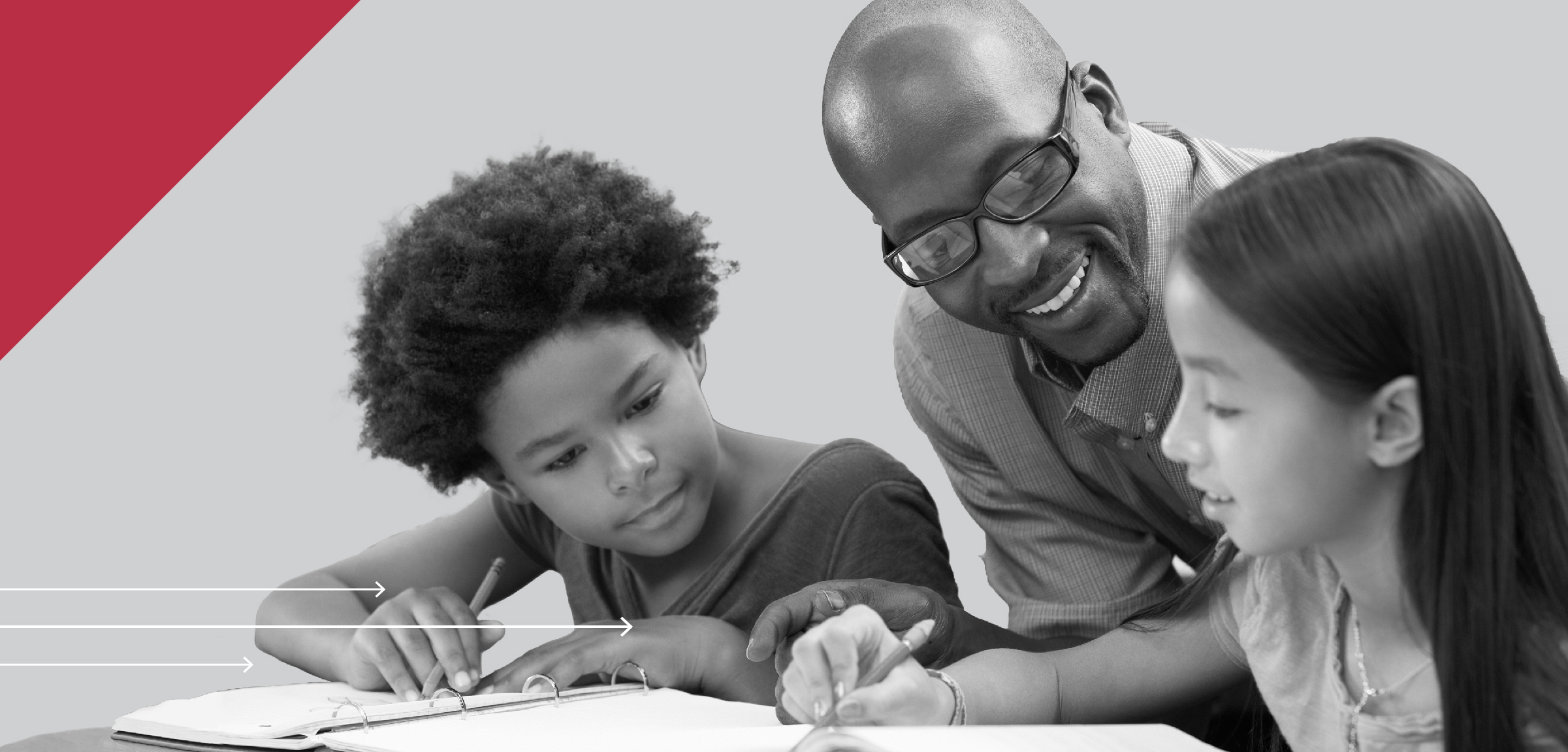 Teacher seated with two students going over work