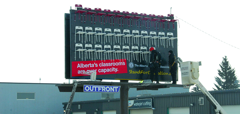 Workers install chairs on an ATA billboard