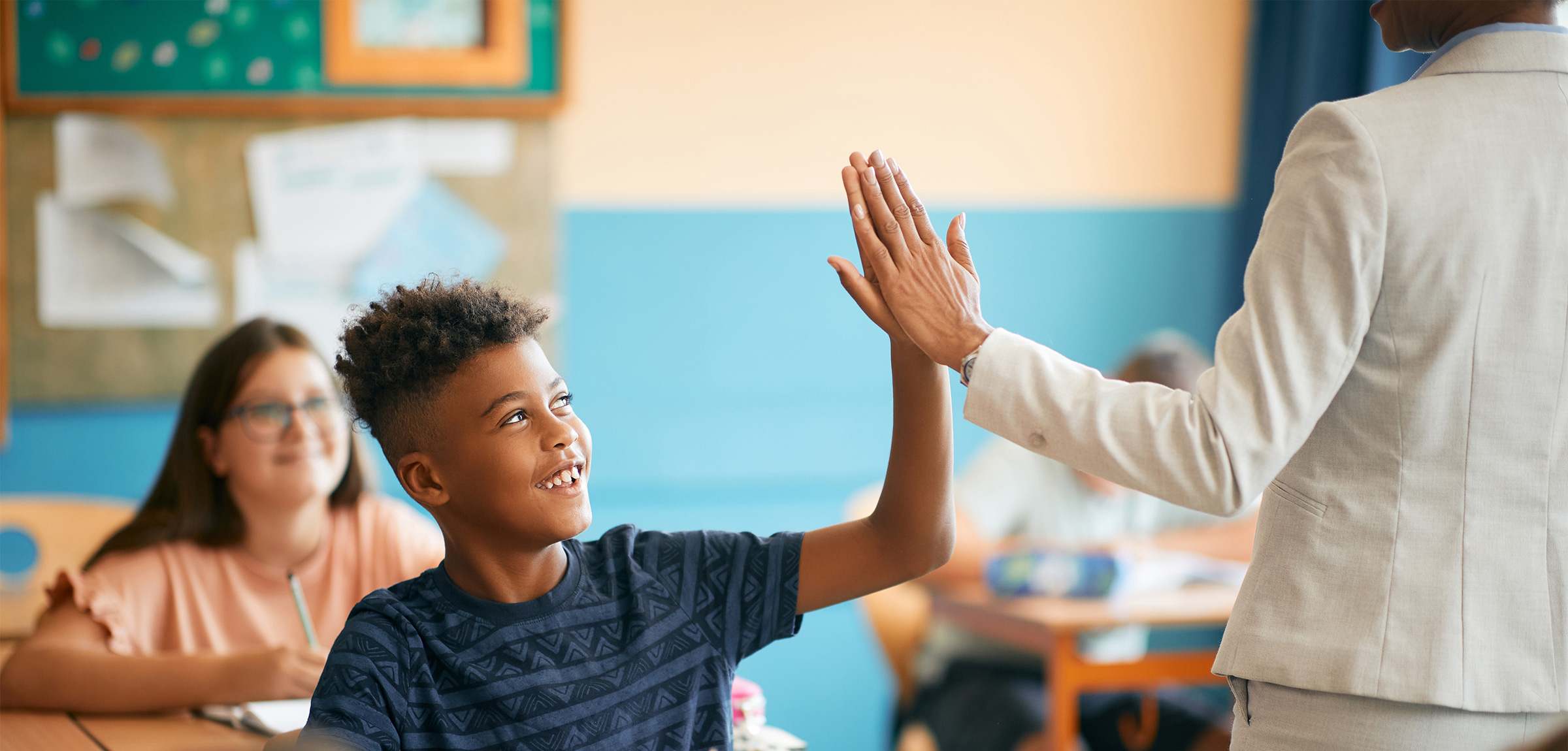 A young black student giving a high five to a teacher