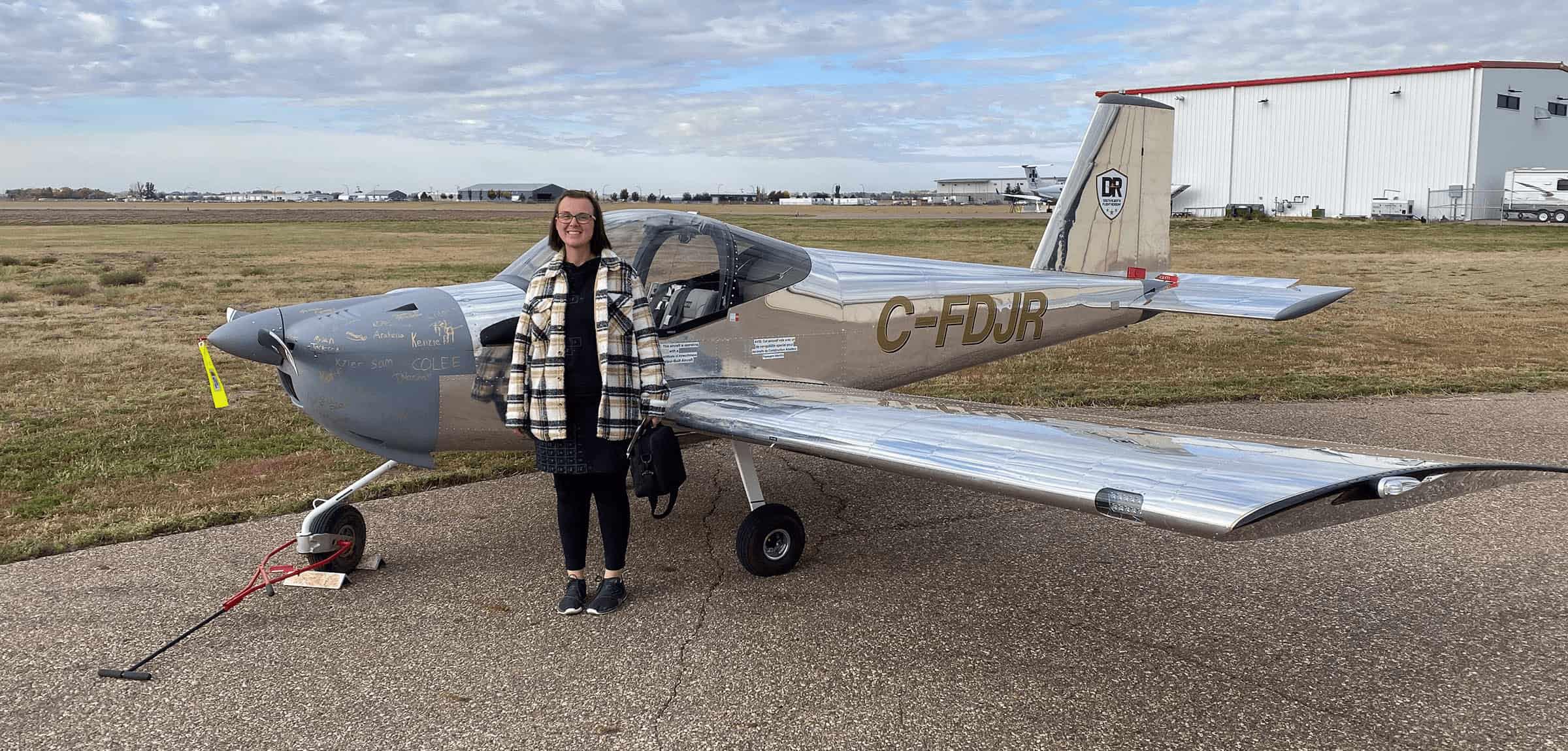 Women standing next to a small silver airplane