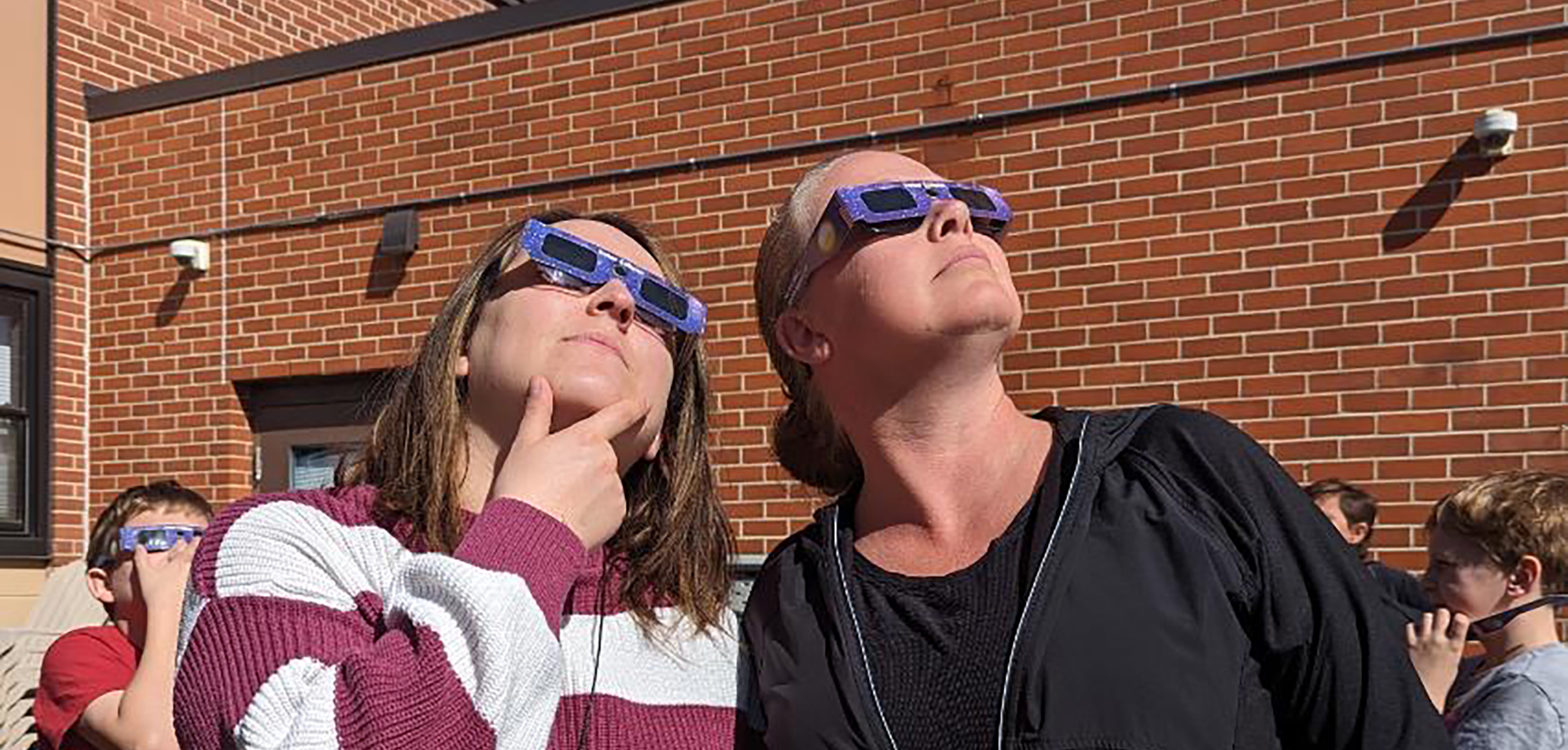 Two women look at the solar eclipse through protective glasses
