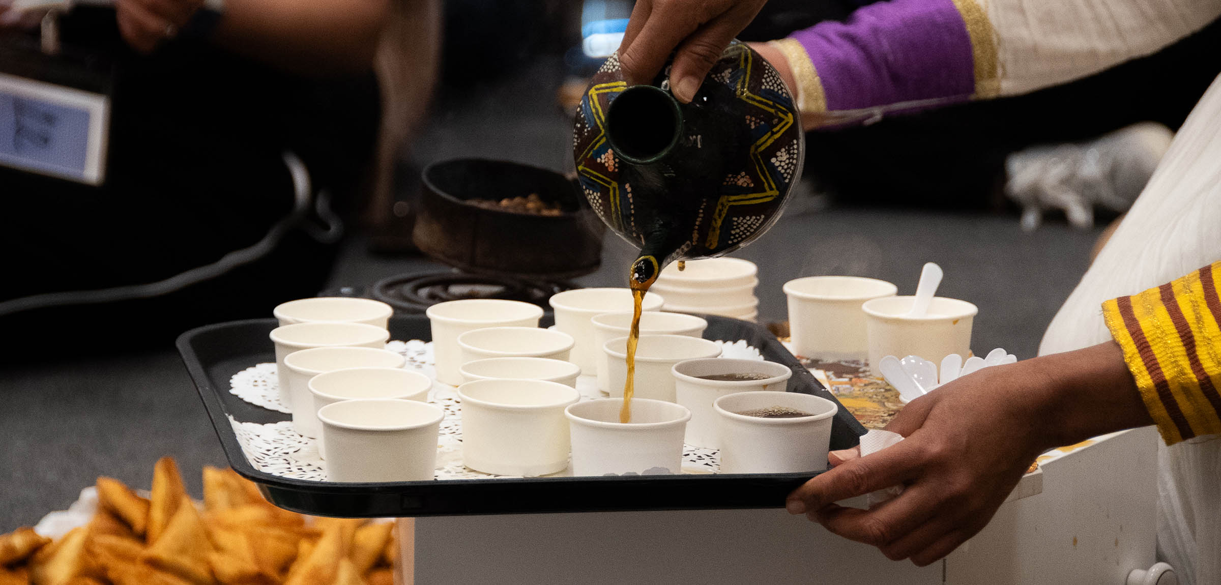 Coffee being poured into small sample paper cups
