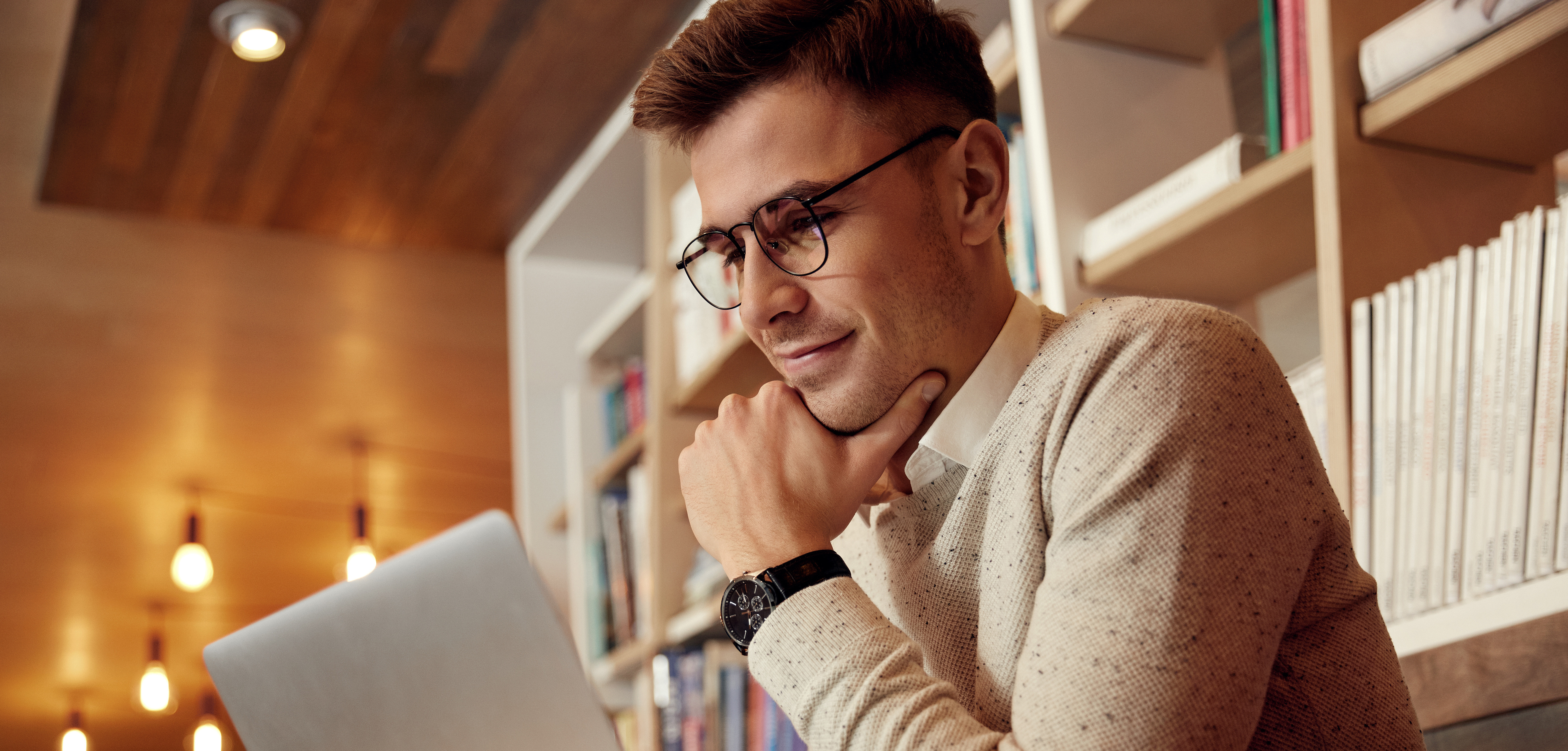 white male viewing laptop screen in a library