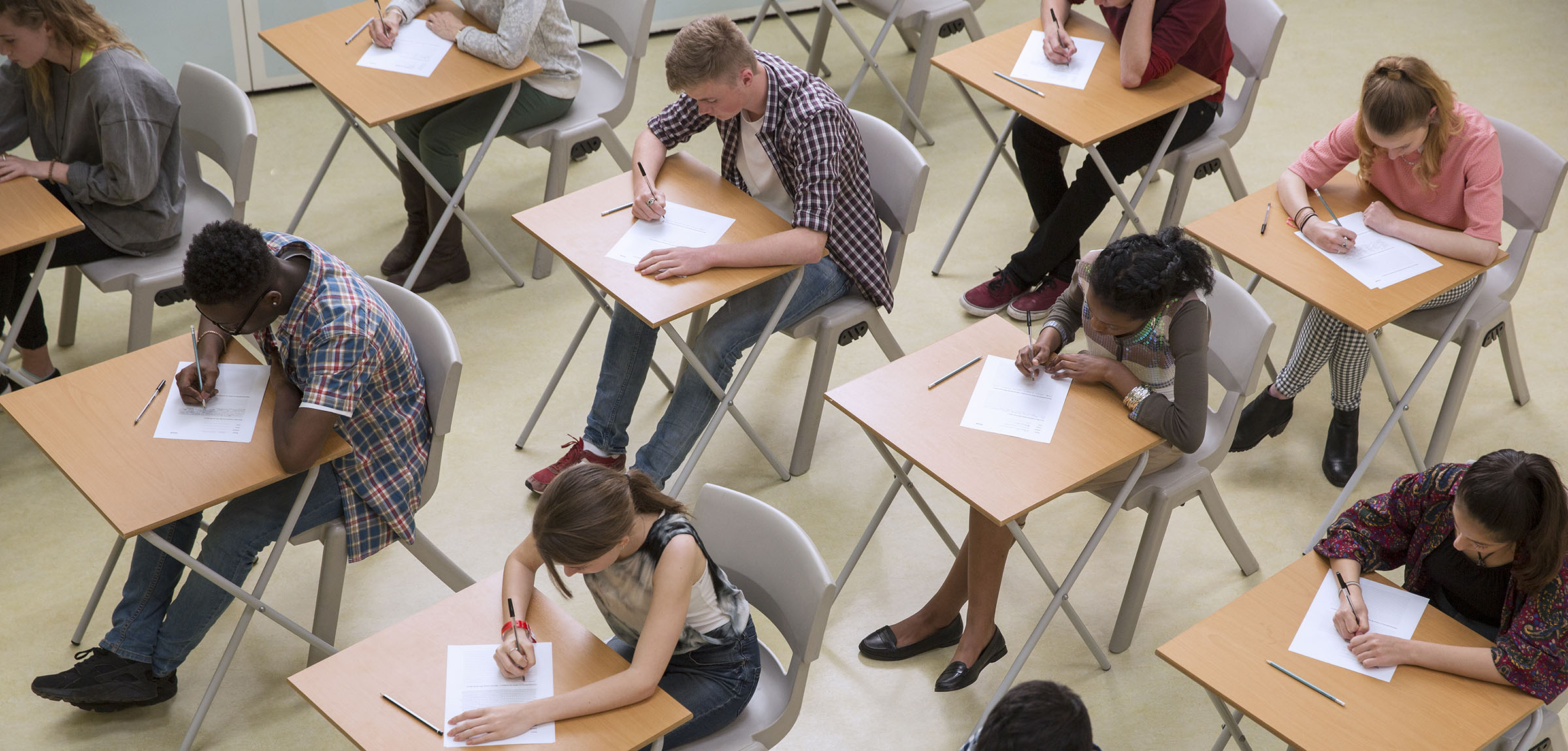 Aerial image of students writing a test in rows of desks