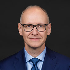 Man with glasses wearing a blue suit and tie