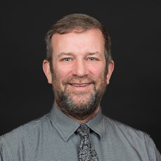 Portrait of a bearded man in a grey shirt and tie