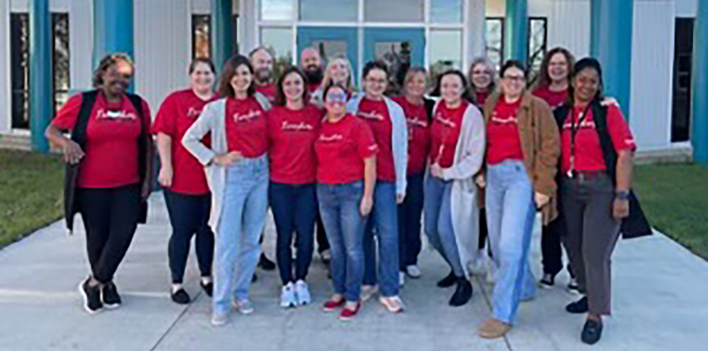 Teachers wearing red for ed t shirts in front of school