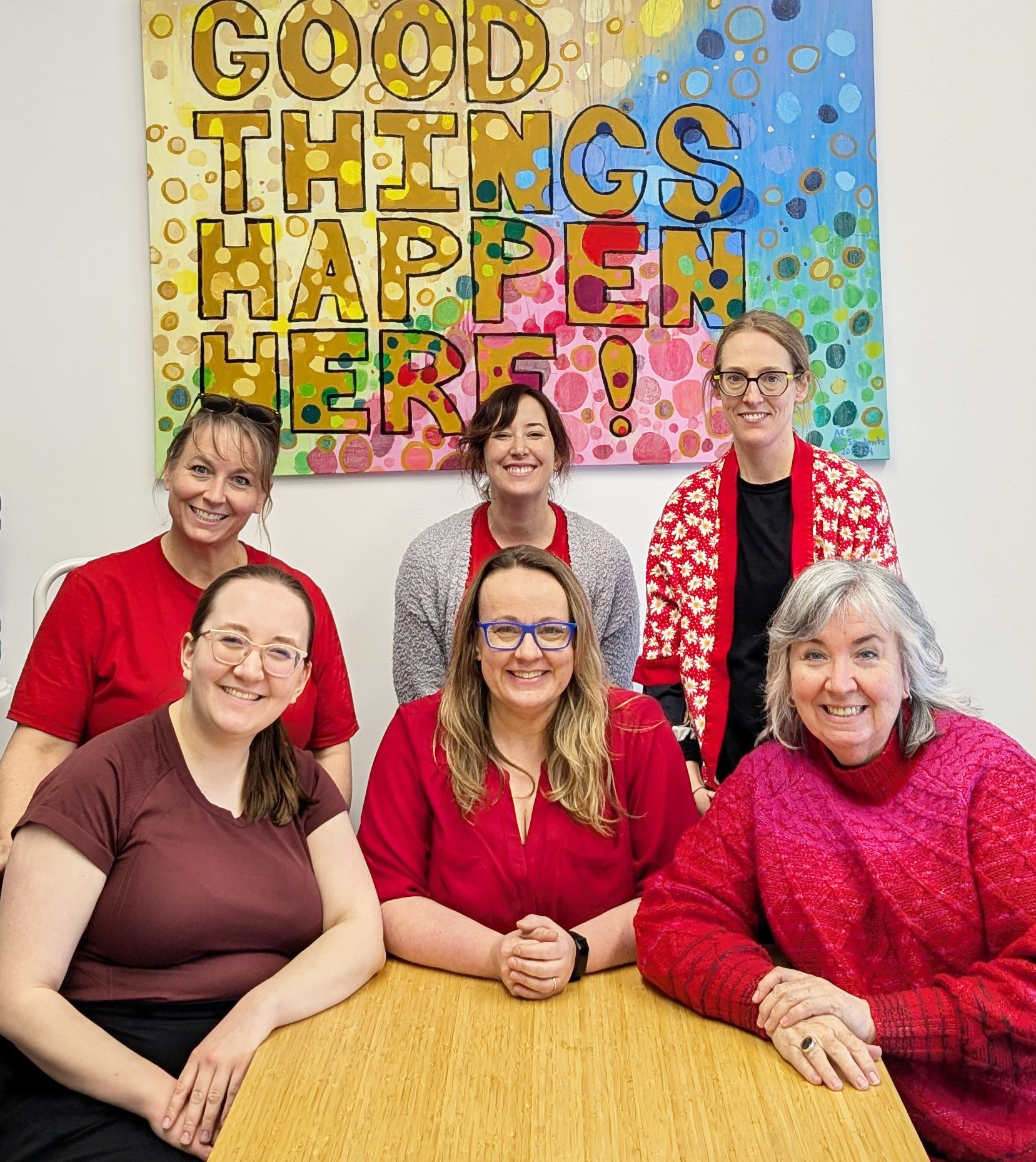 teachers sitting at a table wearing red shirts