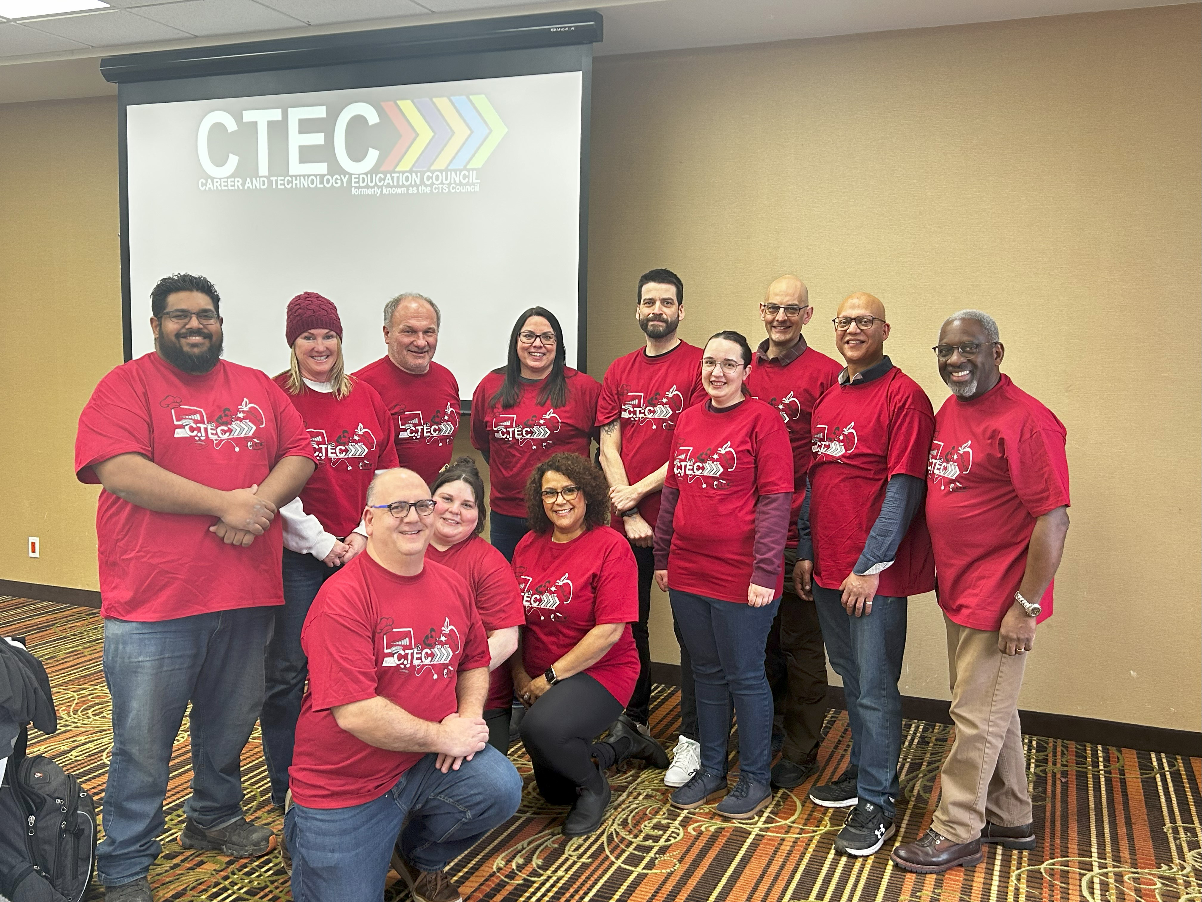 Teachers wearing red shirts stand in front of CTEC screen