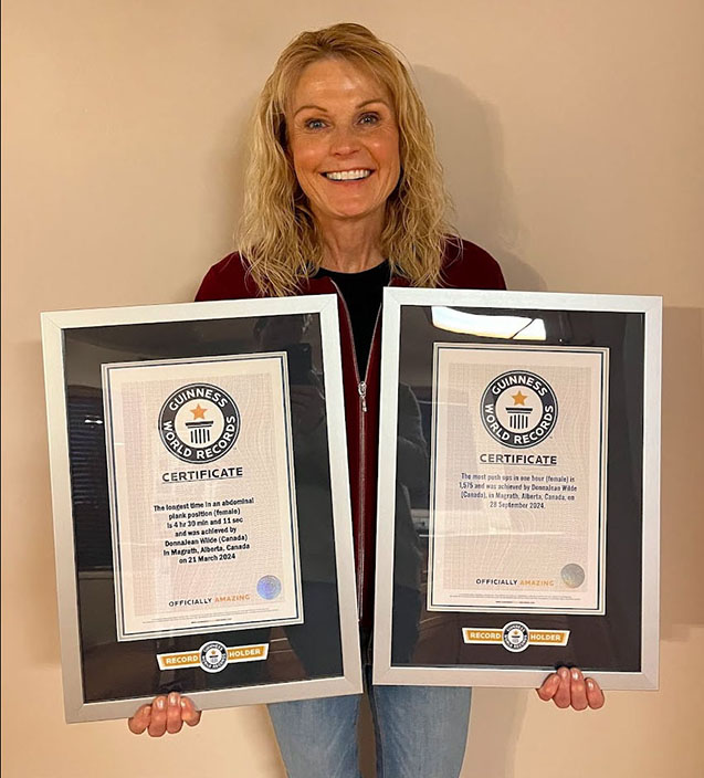 A woman holding two framed Guiness world records