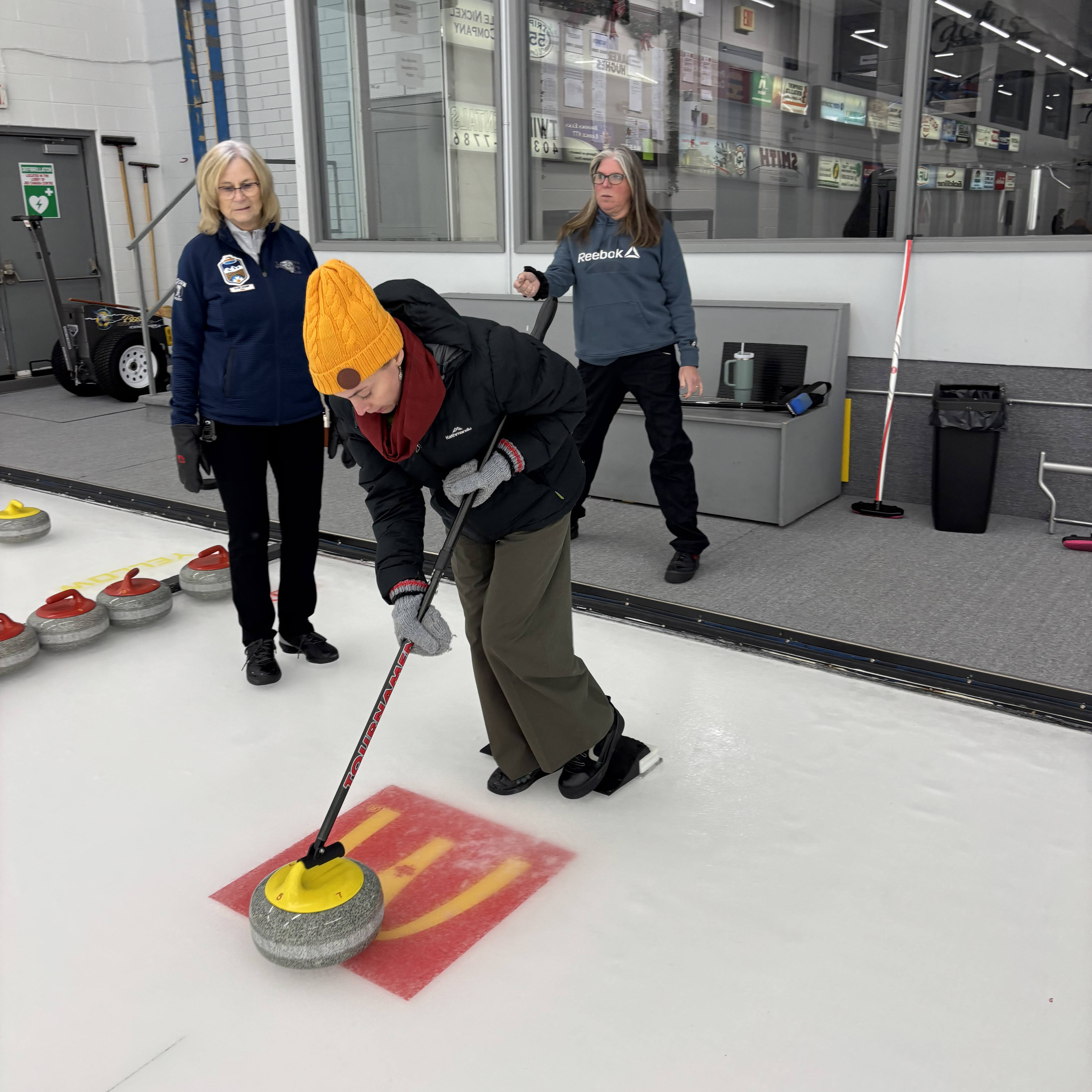 A woman pushing a rock at a curling rink