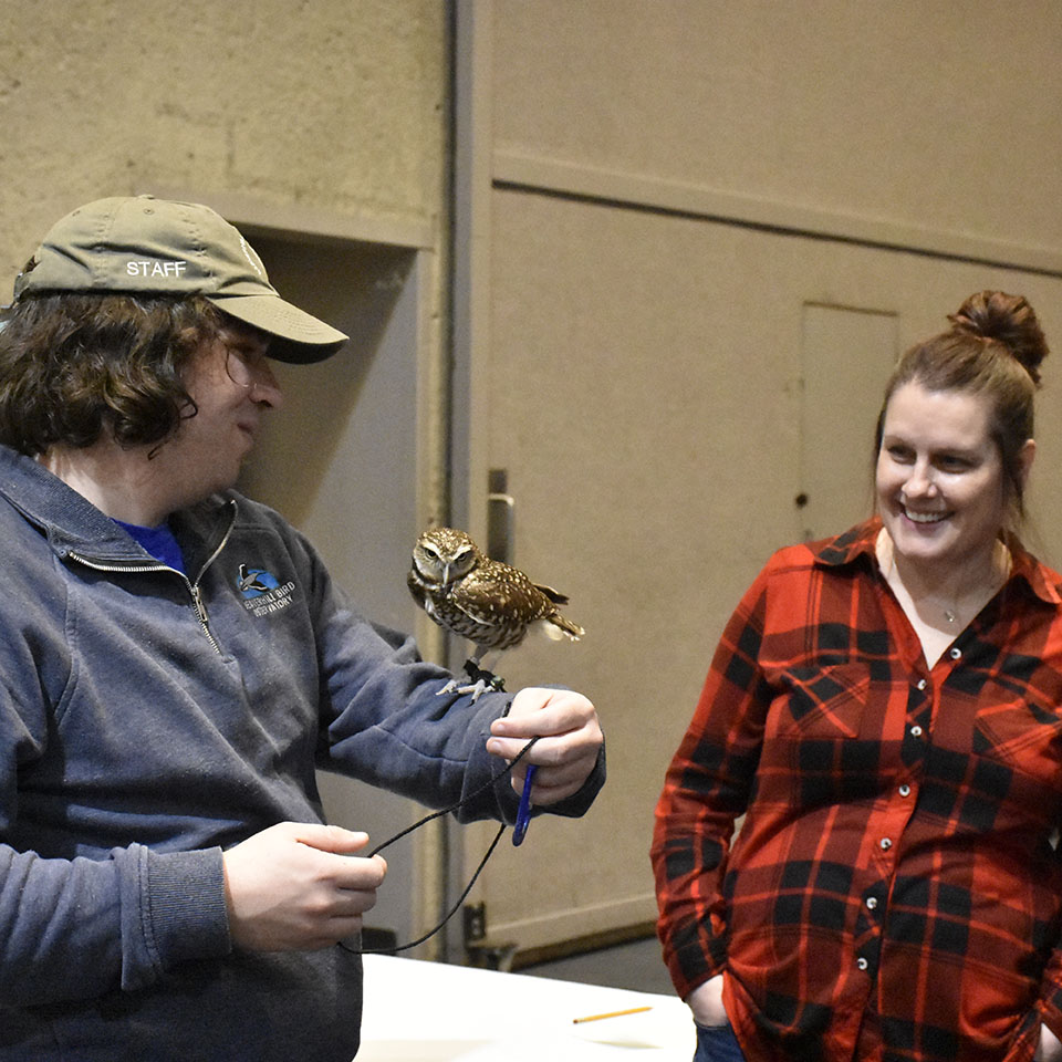 A man holding a small owl on his arm