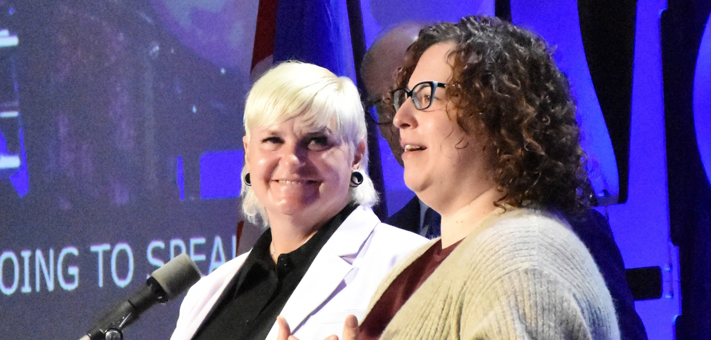 Women receiving award from another women on ARA stage.