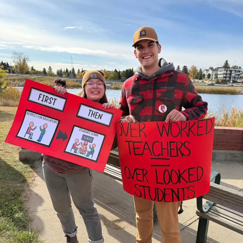 Two people holding signs at a rally