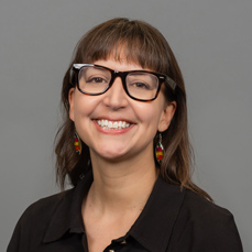 A smiling brunette woman wearing brown glasses