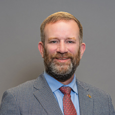 A smiling, beareded man with auburn hair