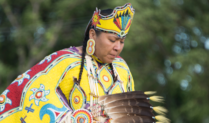 Indigenous woman in regalia dancing in a pow wow.