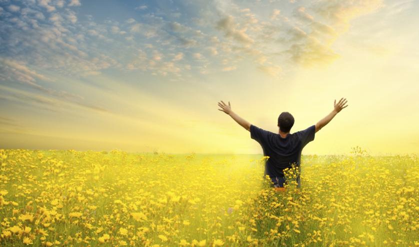 Man standing with his arms raised in a yellow field