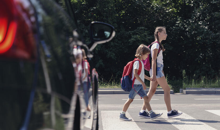 Two children crossing at crosswalk in front of car