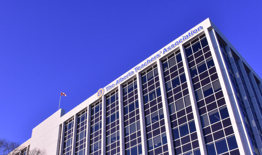 A blue sky background free of clouds. In the foreground is a white building with columns of blue windows. The canadian flag flies from the top of the building. The ATA logo and the text "Alberta Teachers' Association" are also on the front facade.