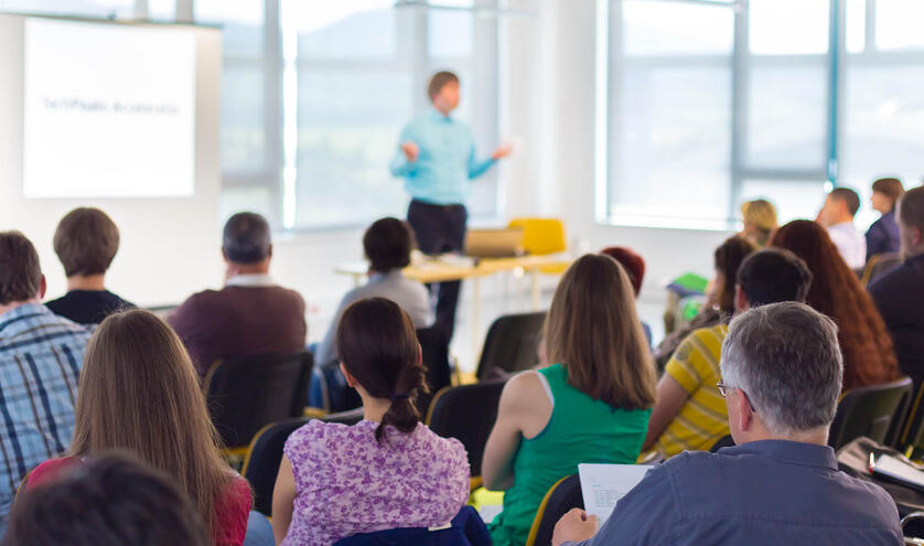 Presenter speaking infront a group of adults