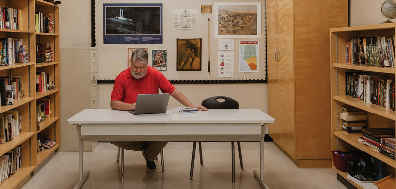 Ben Galeski wears a red shirt at a table in the Library