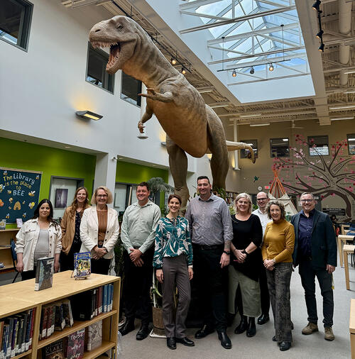 Group of people posing infront of dinosaur