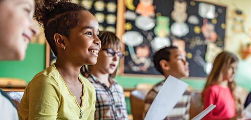 Students engaged with action at the front of the classroom