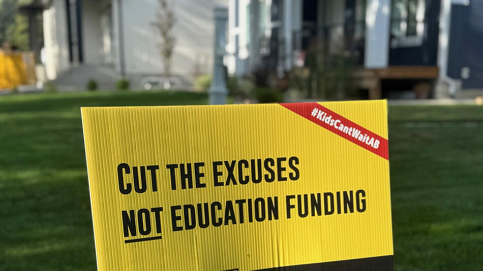 A lawn sign that says "Cut the excuses not education funding"