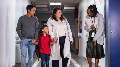 Mother and Father standing in a school hallway with their young son and his teachers