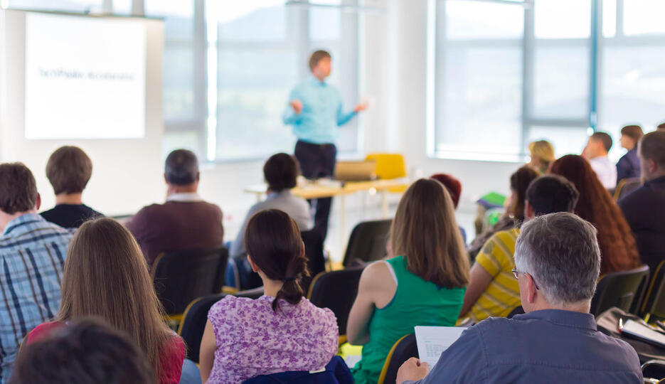 Presenter speaking infront a group of adults