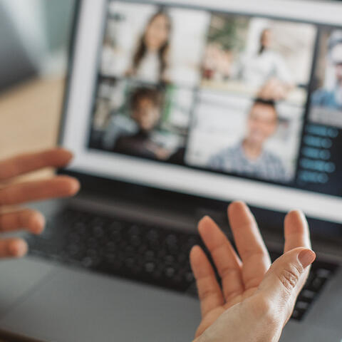 Someone explaining with their hands to a group online chat