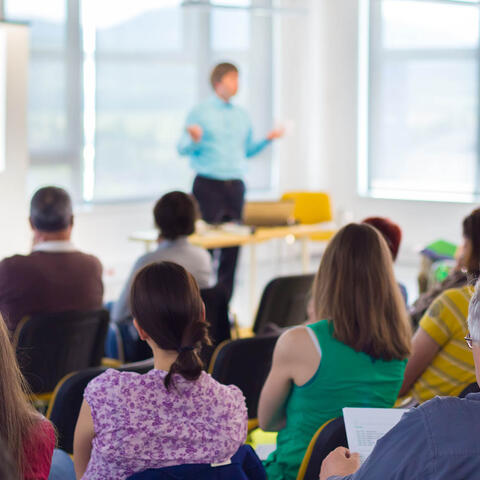 Presenter speaking infront a group of adults