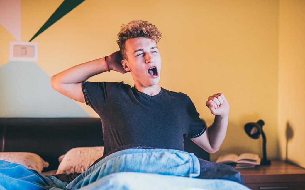 Teenager sitting up in bed, yawning