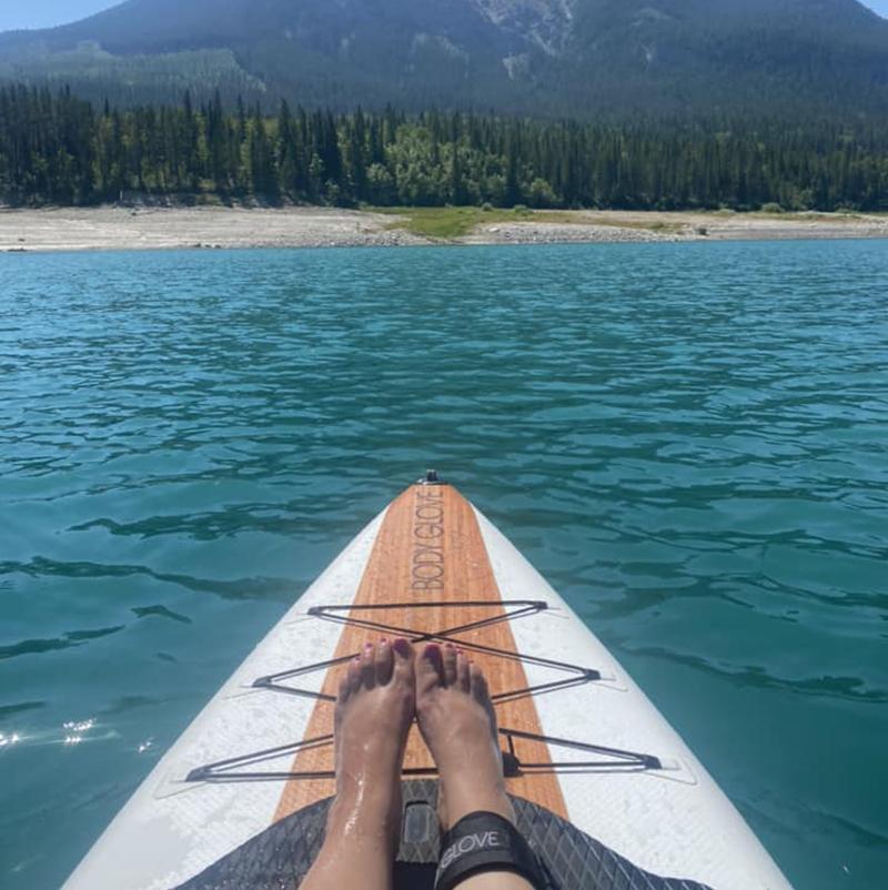 A person's feet resting on a kayak in a lake with a view of the mountains ahead