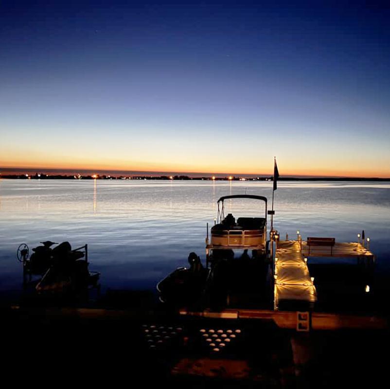 A boat near a dock on a lake at sunset