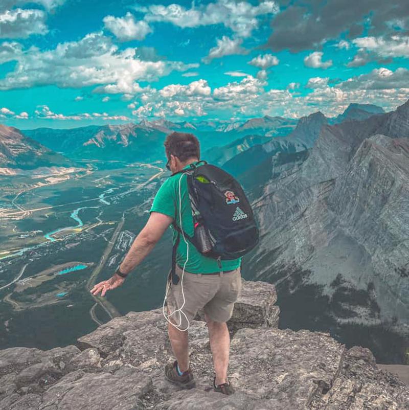 A climber at the top of a mountain looking down into the valley and mountain range