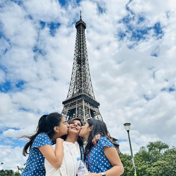 Three women standing at the base of the Eiffel Tower