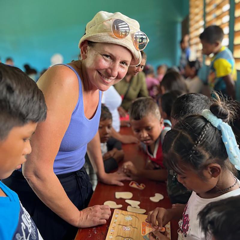 A teacher smiles in a classroom of children