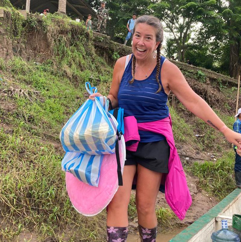 A woman carries bags through a jungle