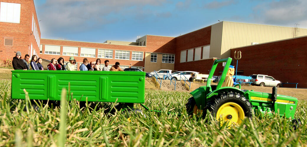 Students appear to be riding in a trailer pulled by a toy tractor