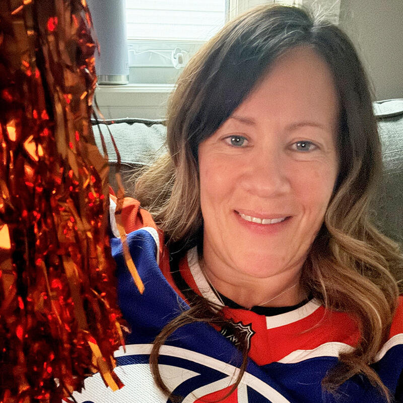 A teacher wears her Oilers jersey and shakes a pom pom