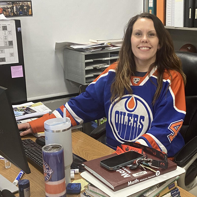 A teacher wears her Oilers jersey at her desk