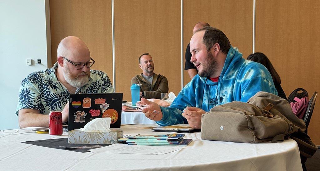 Two men seated at a table talking