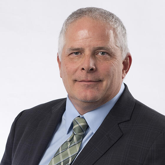 Portrait of grey haired man wearing green tie