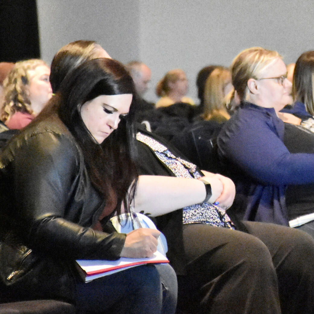 A woman takes notes during a presentation