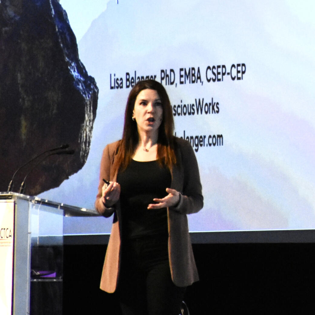 A woman on stage delivering a presentation