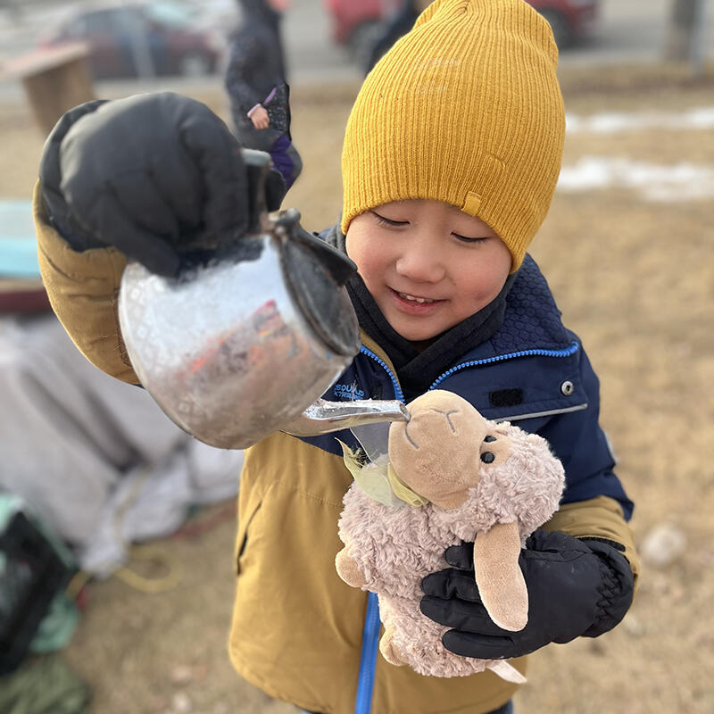 A student pretends to give water to his stuffed animal