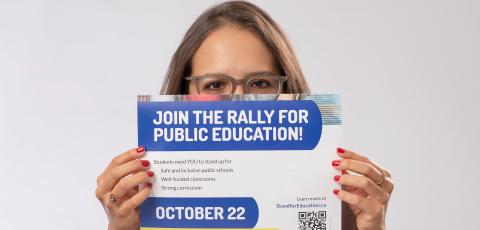 Women with red nails holds a poster for a public education rally on October 22