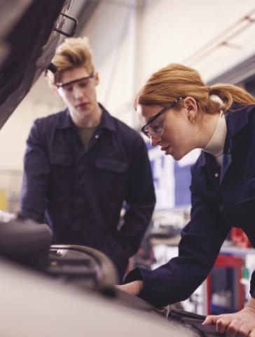 A pair of mechanics examines a car